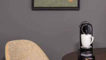 A framed map on a wall, a coffee machine with a cup, and a chair.