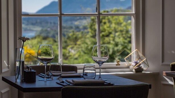 A table set for dining with a view of mountains and greenery through a window. - The Marmalade Hotel (Portree)