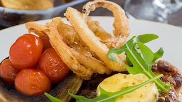 A plate with steak, cherry tomatoes, fried onions, and greens.