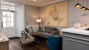 A modern living room with a sofa, armchairs, a coffee table, and a large abstract artwork on the wall. - The Marmalade Hotel (Portree)