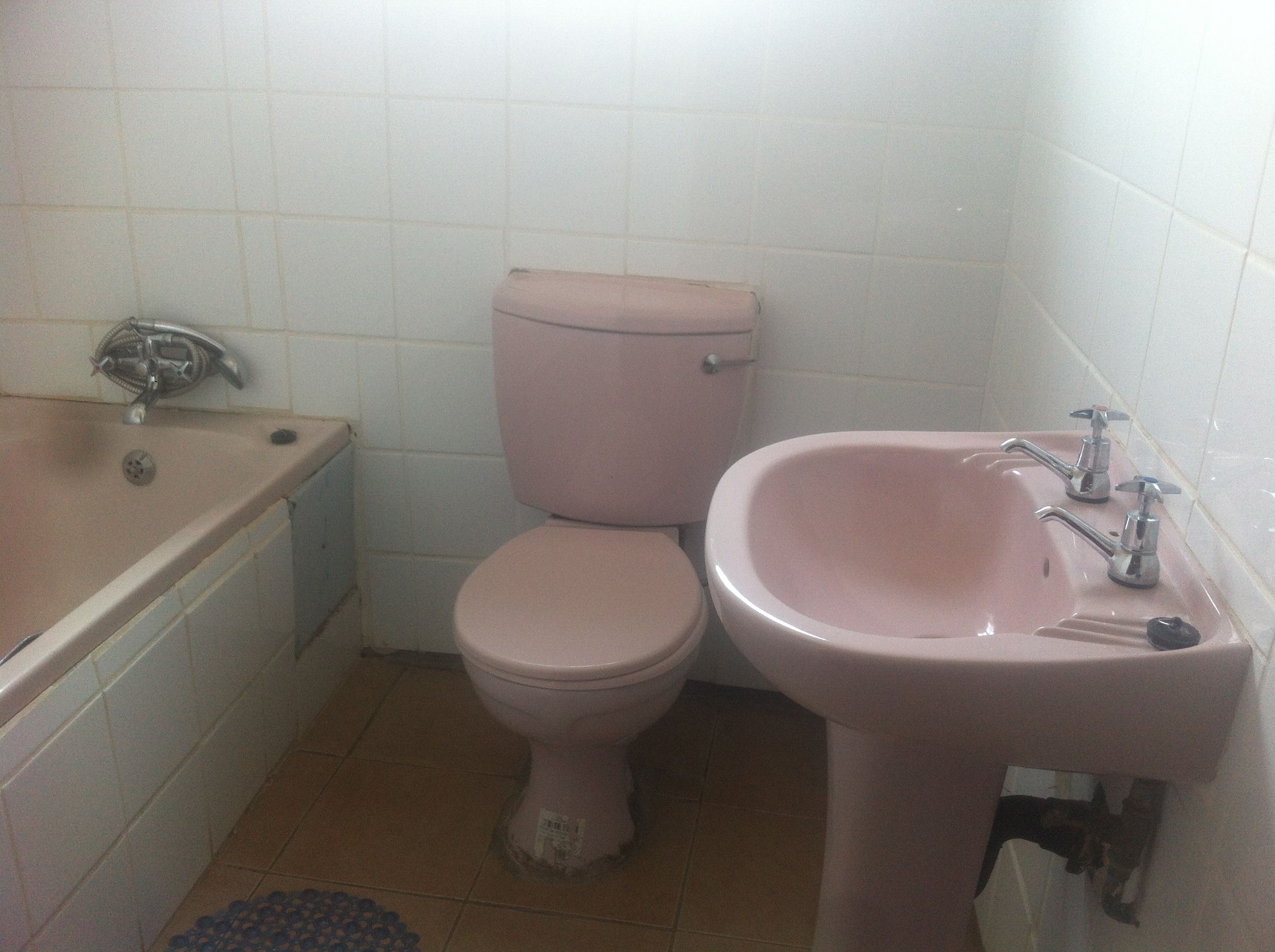 Et badeværelse med toilet i lyserød, en vask og et badekar.