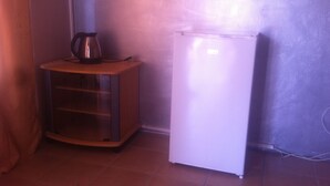A compact kitchen with a refrigerator and a small cabinet. - Jeara Guest House (Serule)