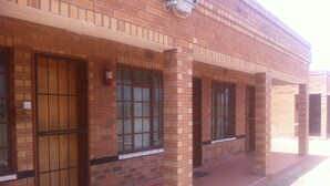 A building with a brick facade, large windows, and a fire extinguisher mounted on the wall. - Jeara Guest House (Serule)