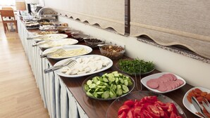 Una barra de buffet con diversos alimentos, incluyendo pepinos en rodajas, tomates y carne.