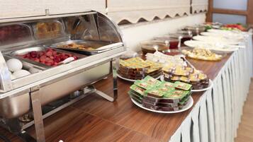Un buffet con diversi alimenti, tra cui uova, salsicce e dolci confezionati.