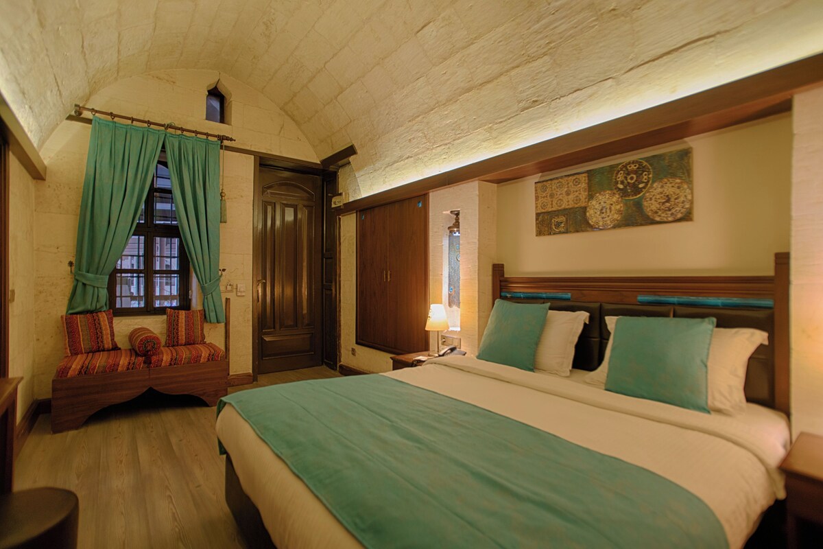A room with a large bed, a wooden bench, a door, and a wall with decorative plates.