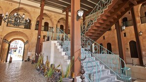 A spacious interior with a grand staircase, arched ceilings, and a series of columns. - Sirehan Hotel (Gaziantep)