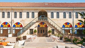 A building with a courtyard featuring outdoor seating and a staircase leading to an upper level. - Sirehan Hotel (Gaziantep)
