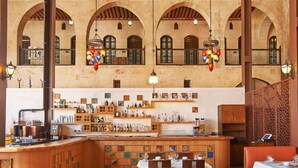 A restaurant with a central bar, wooden tables, and a high arched ceiling with hanging light fixtures. - Sirehan Hotel (Gaziantep)