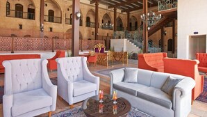 A spacious indoor area with high ceilings and arches, featuring seating arrangements and a staircase. - Sirehan Hotel (Gaziantep)