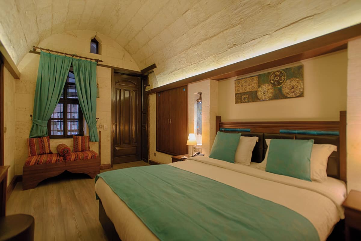 Ein Zimmer mit einem großen Bett, einer hölzernen Bank, einer Tür und einer Wand mit Dekorationen.