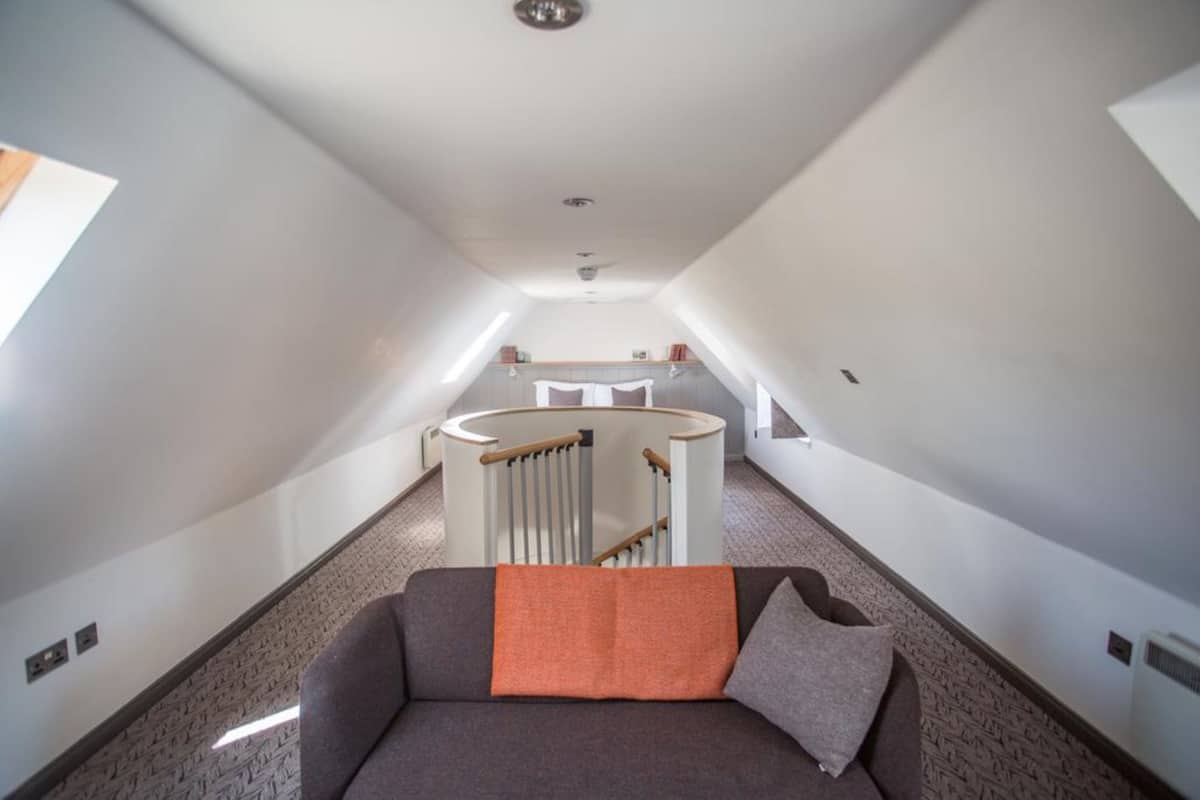 A narrow hallway with a sofa and a circular staircase.