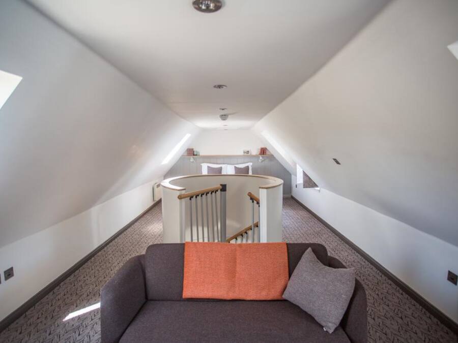 A narrow hallway with a sofa and a circular staircase.