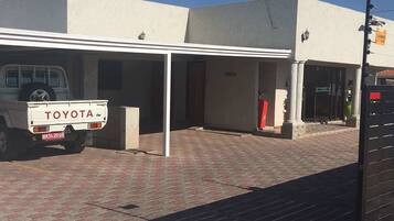 A building with a covered entrance, a white pickup truck parked in front, and a red fire hydrant nearby.