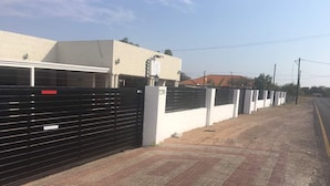 A gated property with a paved driveway leading to a garage. - Eagle Suites Guest House (Ghanzi)