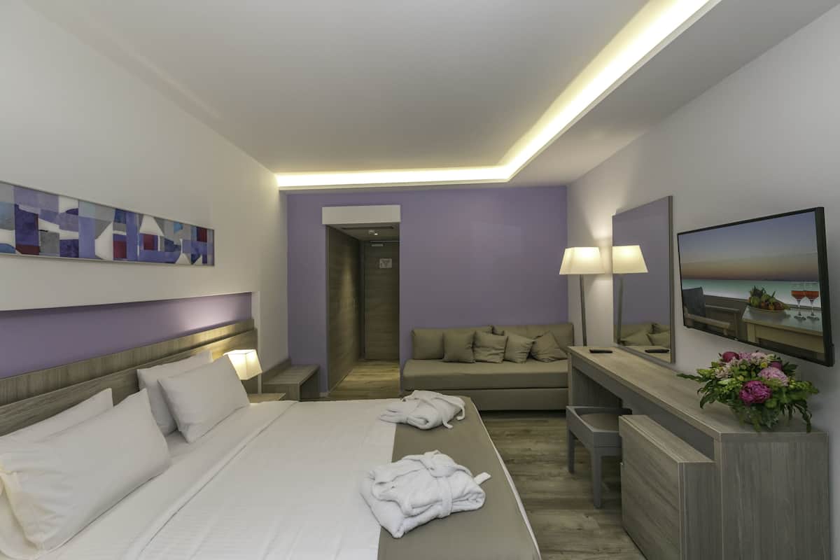 Ein modernes Hotelzimmer mit einem großen Bett, einer Couch, einem Schreibtisch und einem Gemälde an der Wand.