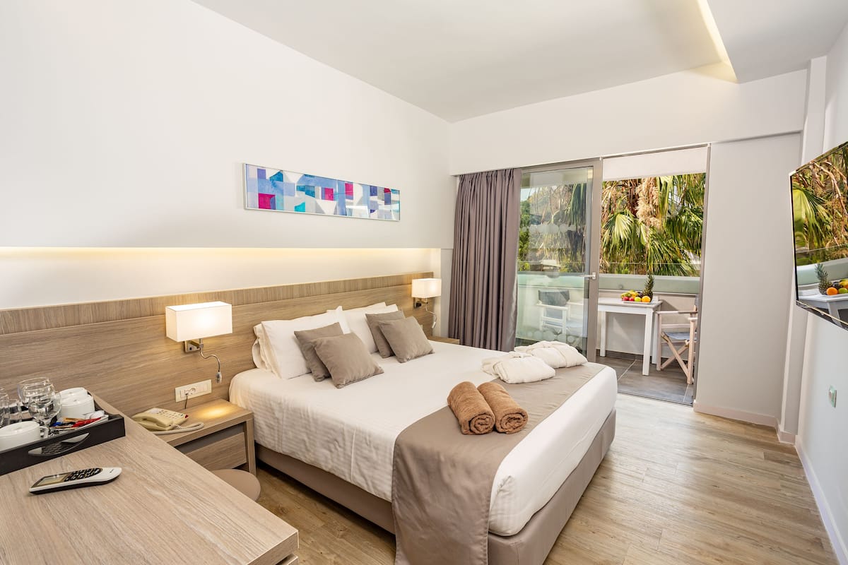 Une chambre d’hôtel avec un lit, une table de chevet, une lampe et une vue sur l’extérieur.