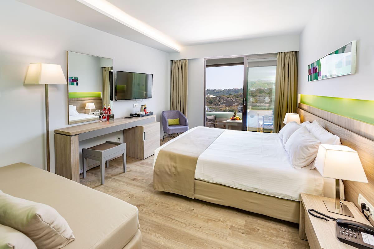 Ein Hotelzimmer mit Bett, Schreibtisch, Stuhl, Fernseher und einem Balkon mit Aussicht.