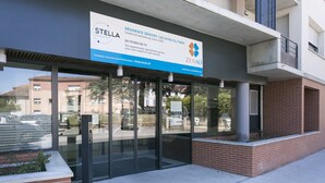 L’entrée d’un immeuble, avec une enseigne indiquant « STELLA Management » et « ZENAO », dotée de portes en verre et d’un socle en briques.