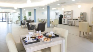 Un grand espace dédié à la salle à manger, avec des tables et des chaises, une machine à café et un comptoir de buffet.