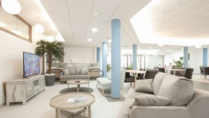 Un hall d’hôtel moderne avec un canapé, une table basse et un téléviseur.