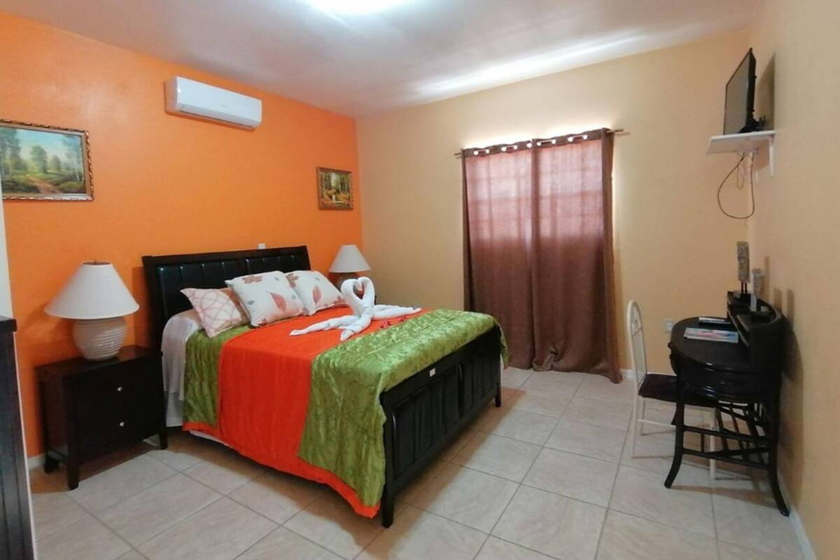 A bedroom with a bed, a desk, a chair, a lamp, and a curtain.