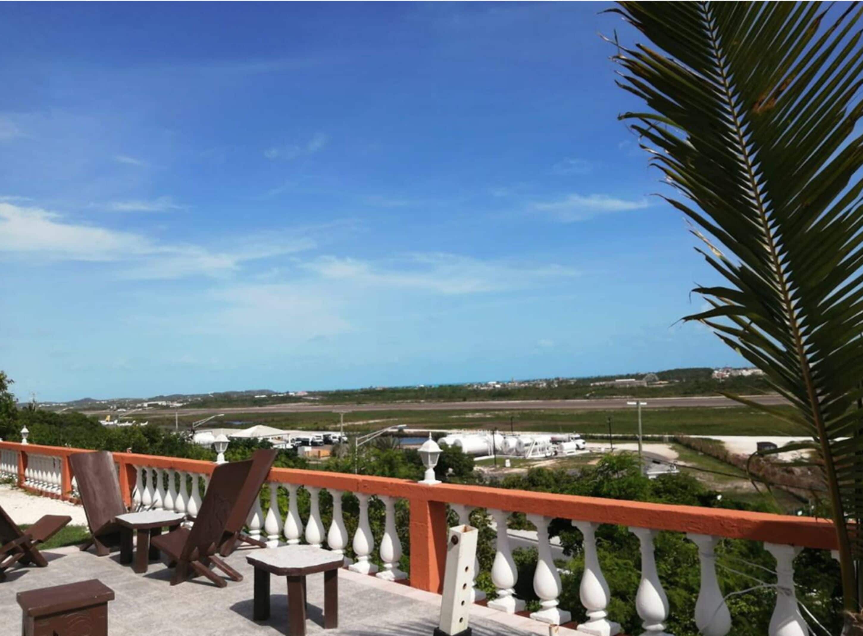 A balcony with outdoor furniture, a view of a runway, and a clear sky.