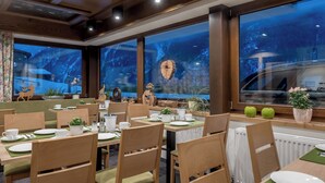 A restaurant with wooden furniture, green table mats, and large windows with a view of a forest. - Apart Hotel Garni Wieser - Sölden (Soelden)