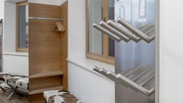 A modern bathroom with a wooden bench, a mirror, and a towel rack.