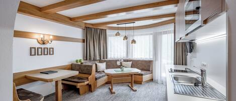 A compact living space with a kitchenette, a dining area, and a seating area with a sofa and bench.