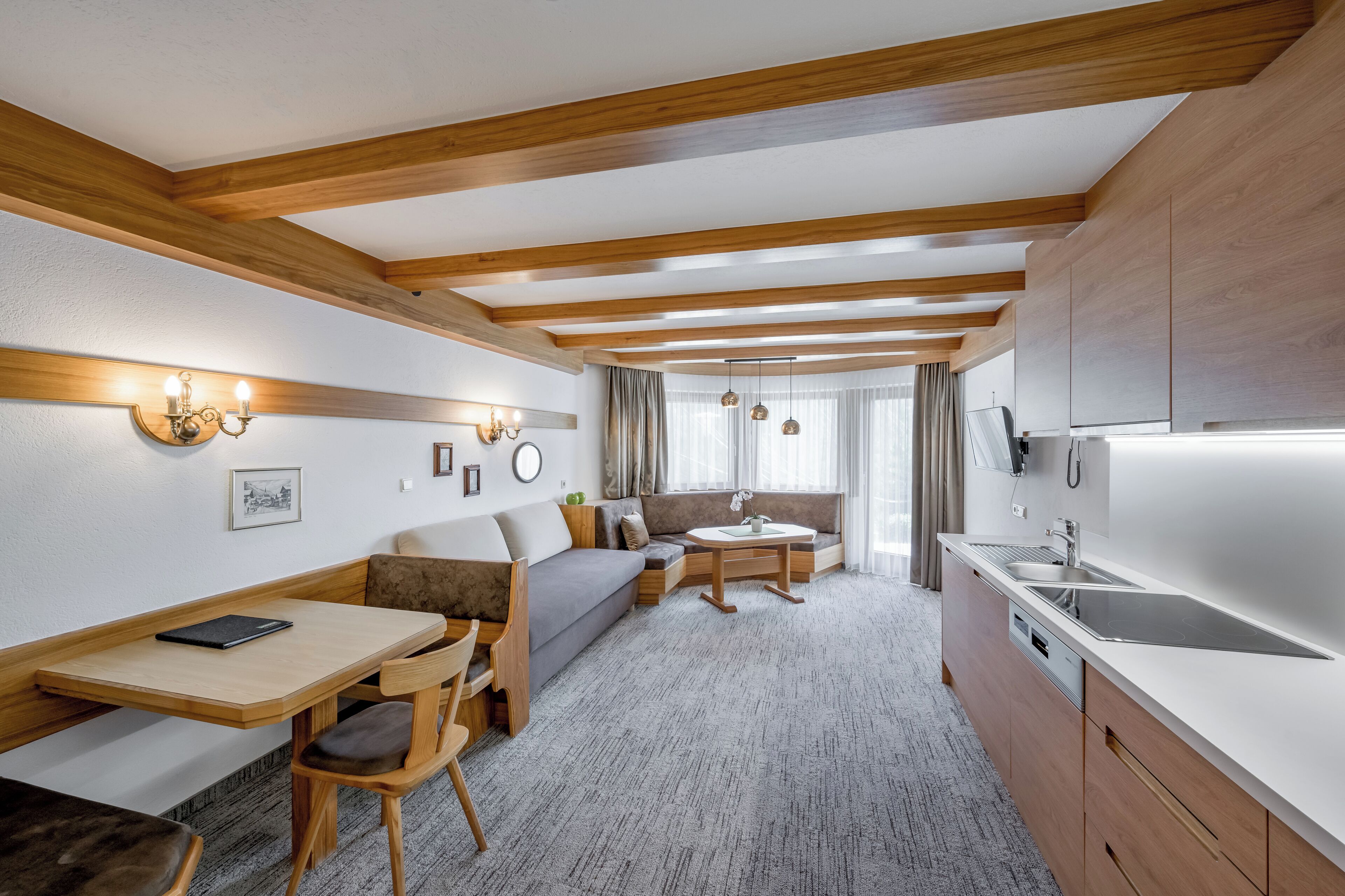 Un espacio habitable compacto con kitchenette, comedor y zona de estar con sofá y sillas.