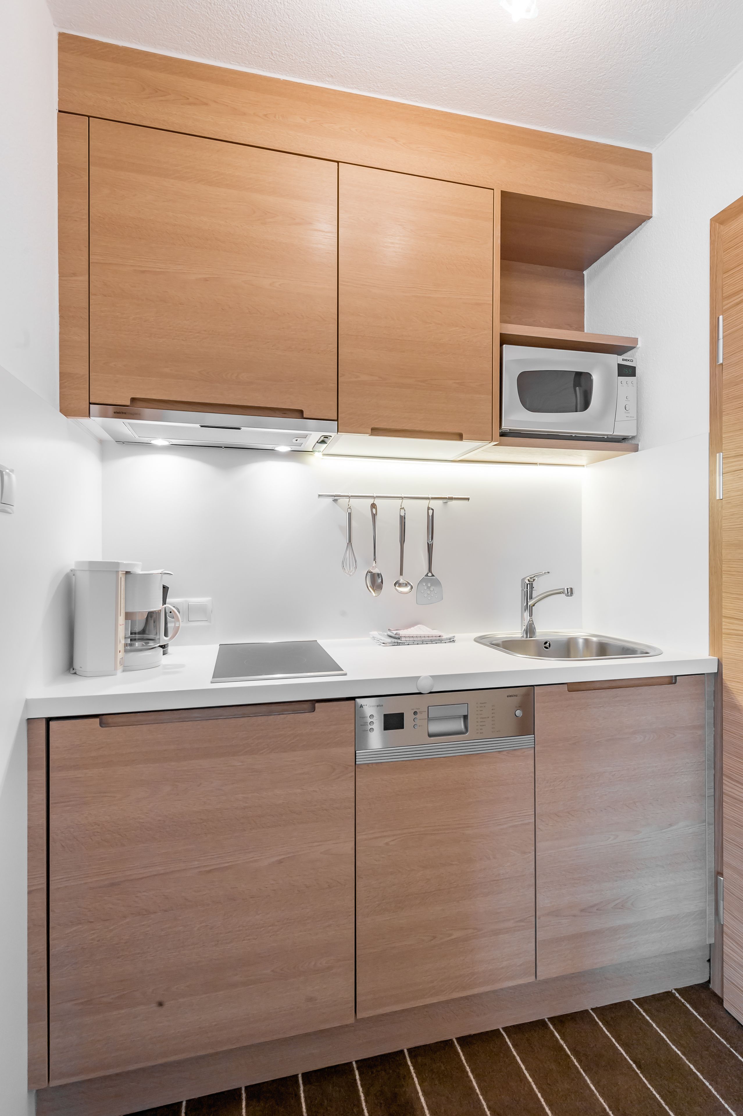 Una cocina moderna con armarios de madera, microondas, cafetera y lavavajillas.