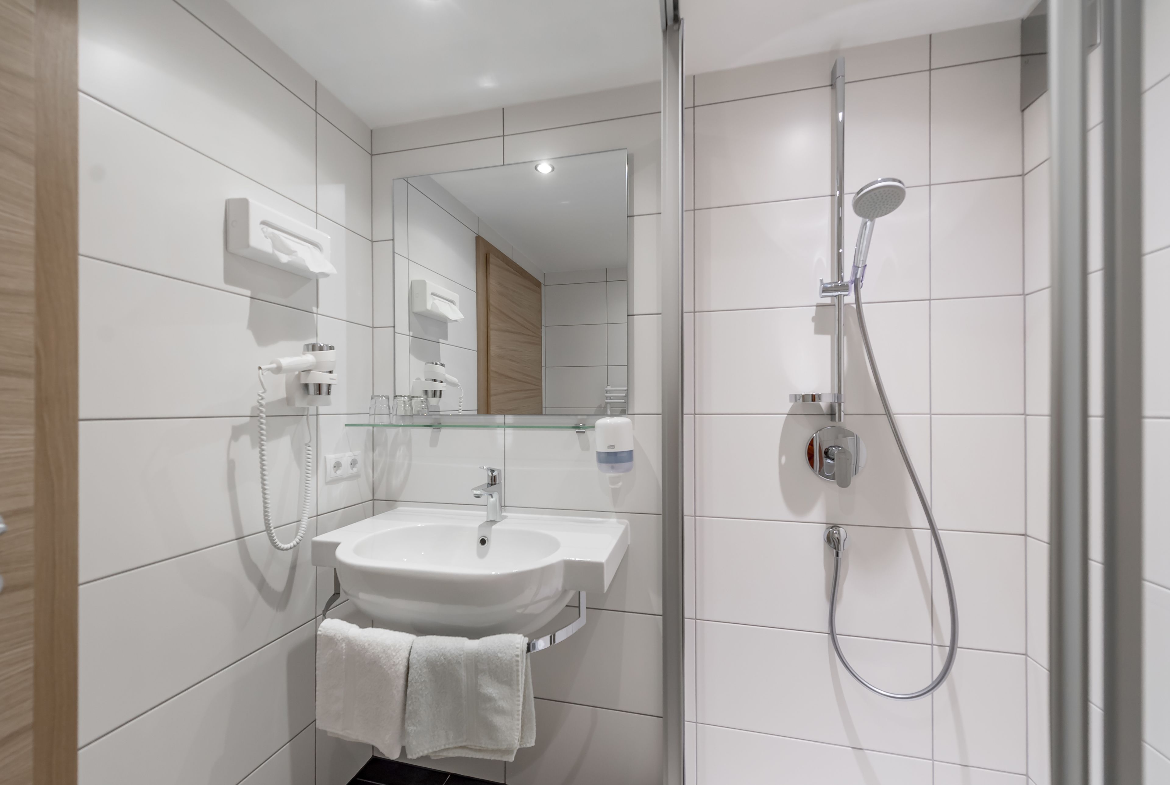 A modern bathroom with a white sink, mirror, and shower.