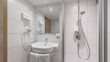 A modern bathroom with a white sink, mirror, and shower.