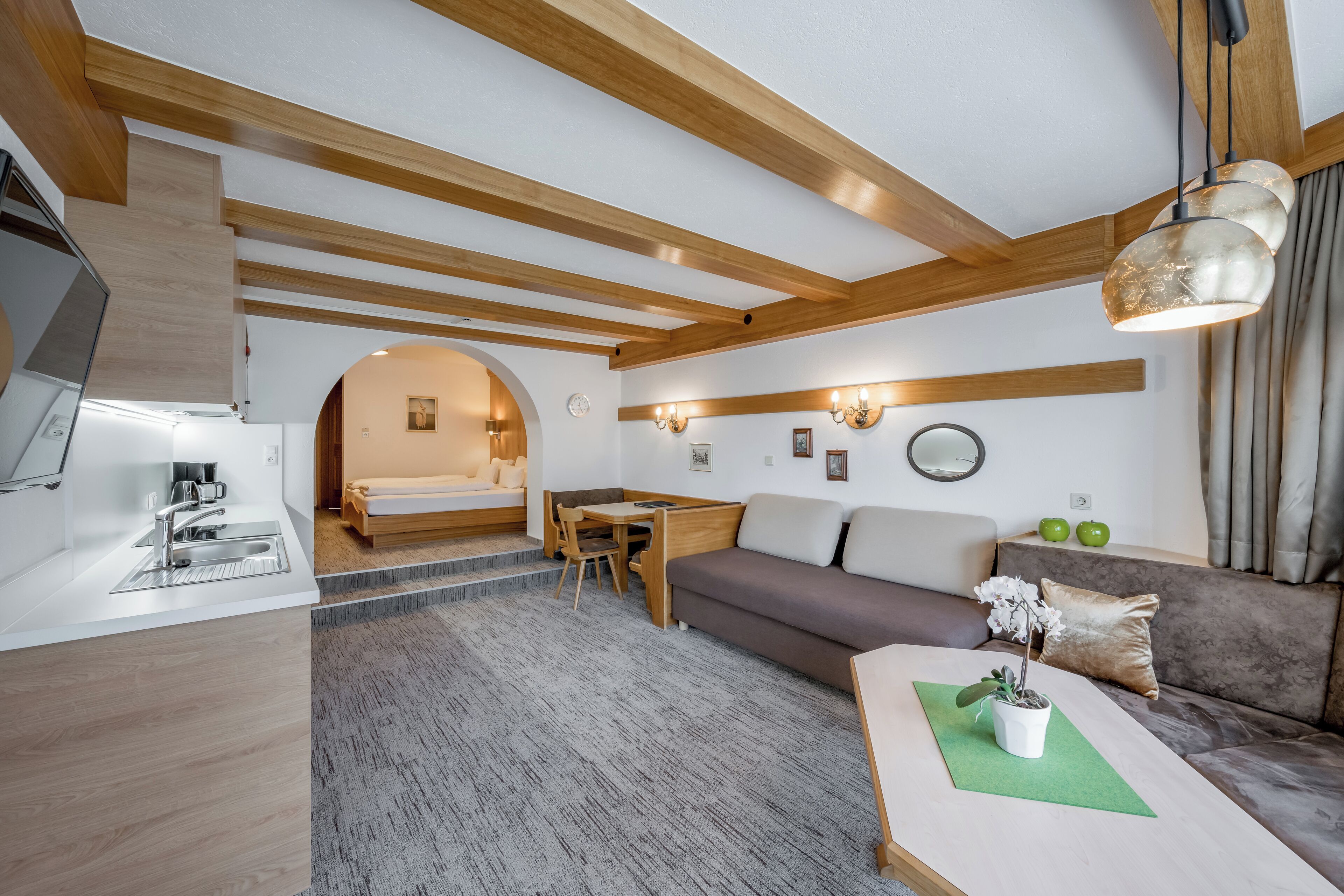 Une chambre d’hôtel moderne dotée d’une kitchenette, d’un canapé, d’un coin repas et d’une grande fenêtre.