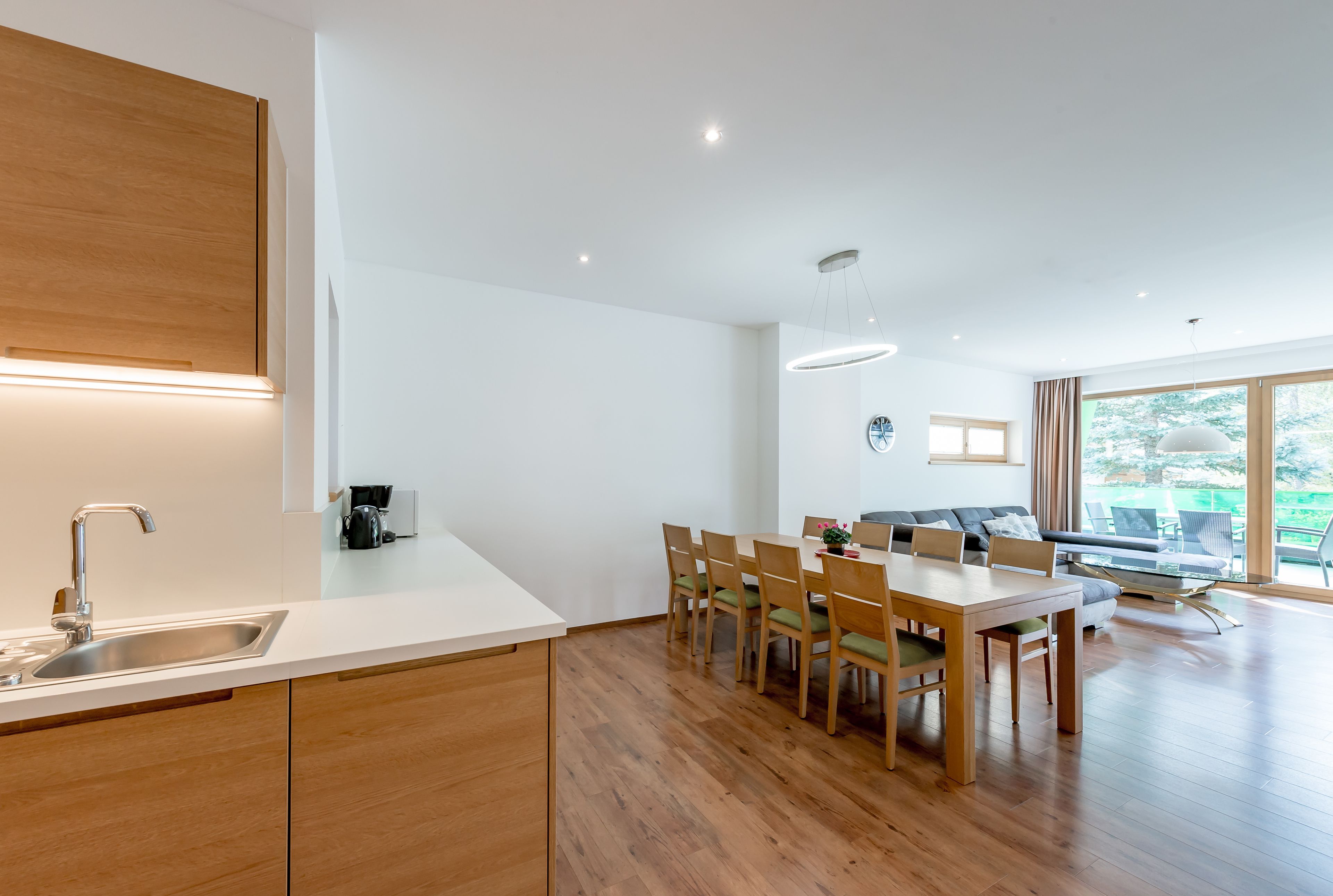 Una cocina moderna con encimera de madera, pileta integrada y zona de comedor con mesa y sillas de madera.