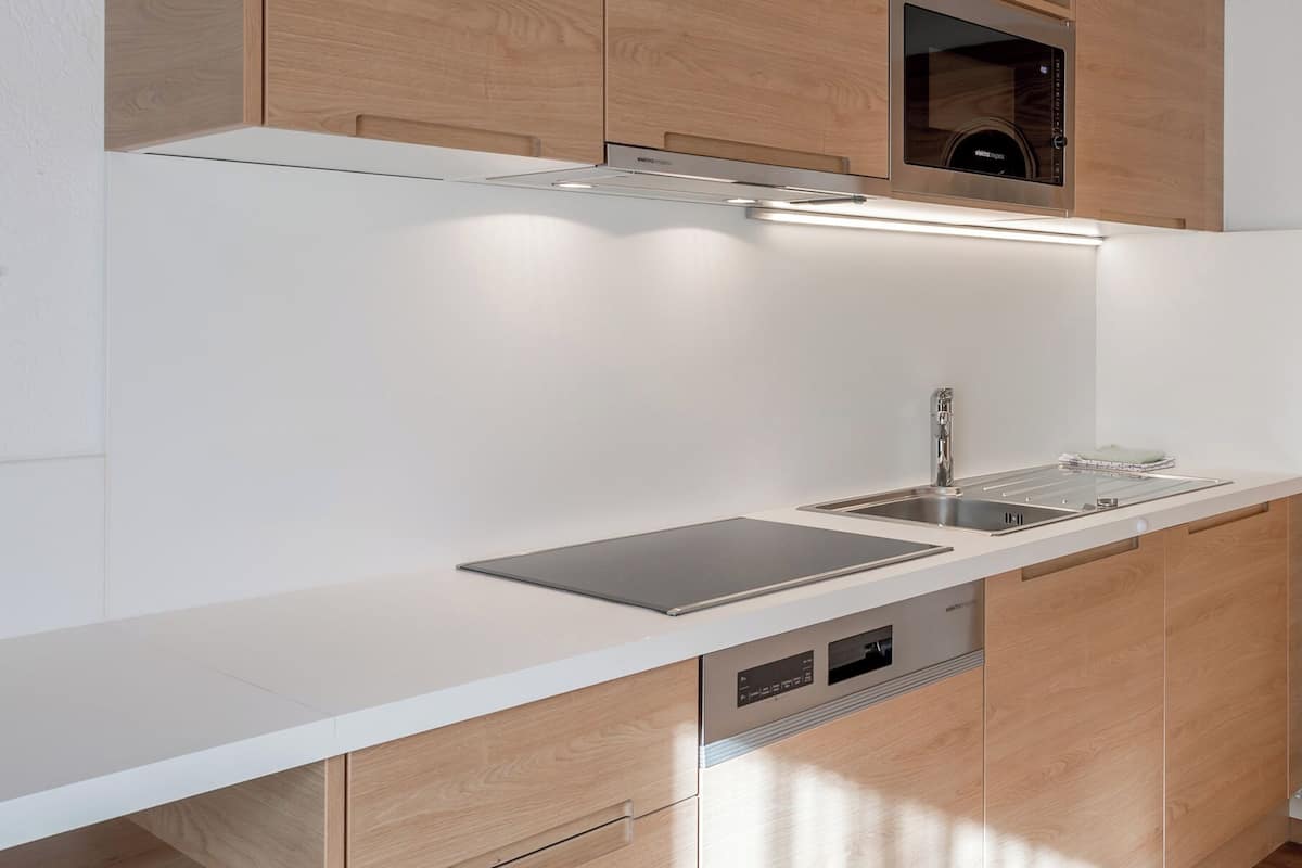 A modern kitchen with wooden cabinets, a stainless steel sink, and a built-in oven.