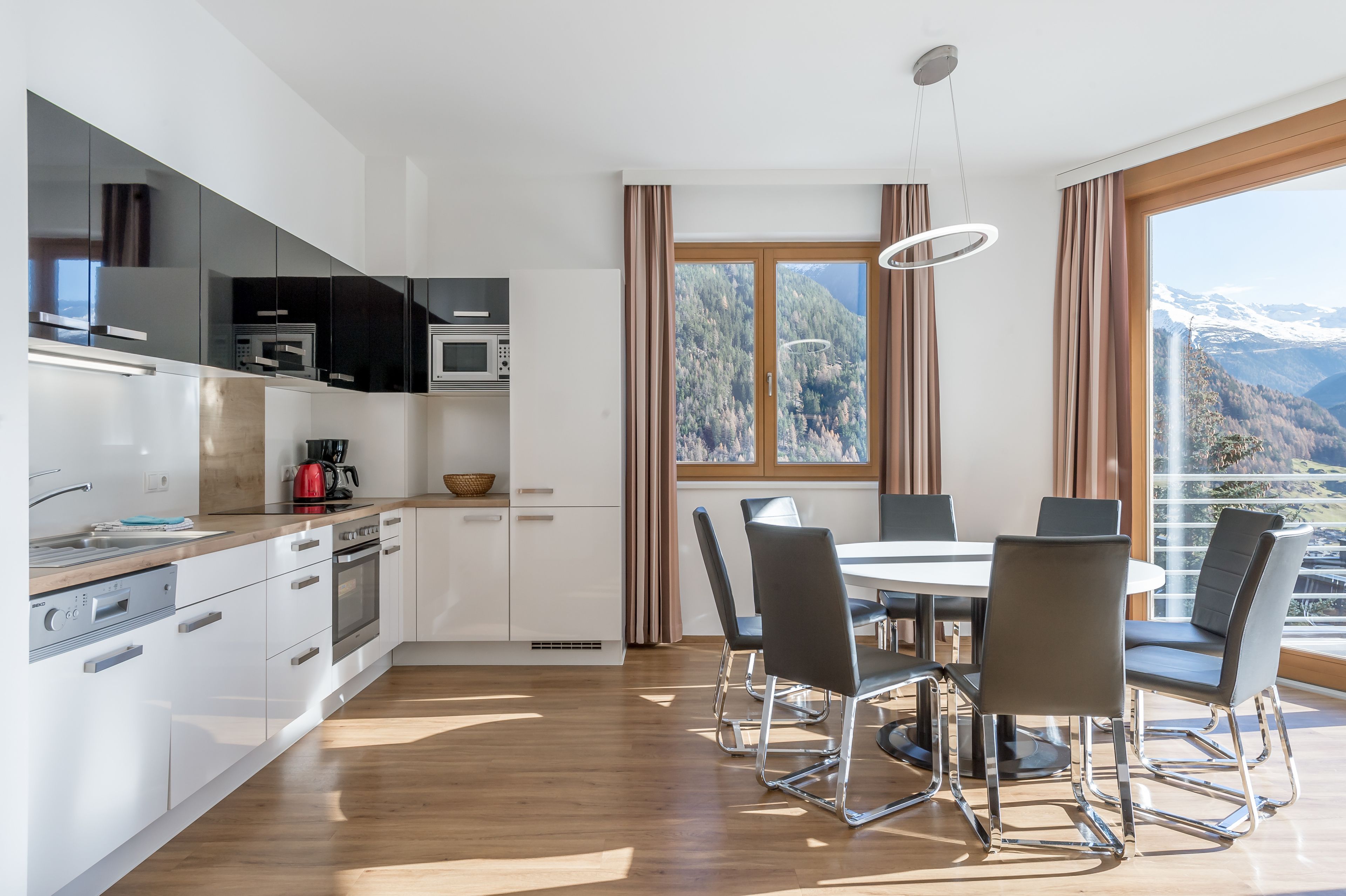 A modern kitchen with white cabinets, a wooden countertop, and a dining area with a round table and chairs.