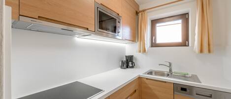 A modern kitchen with wooden cabinets, a built-in microwave, a coffee maker, and a dishwasher.