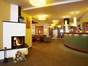 A hotel lobby with a fireplace, seating area, and a bar.