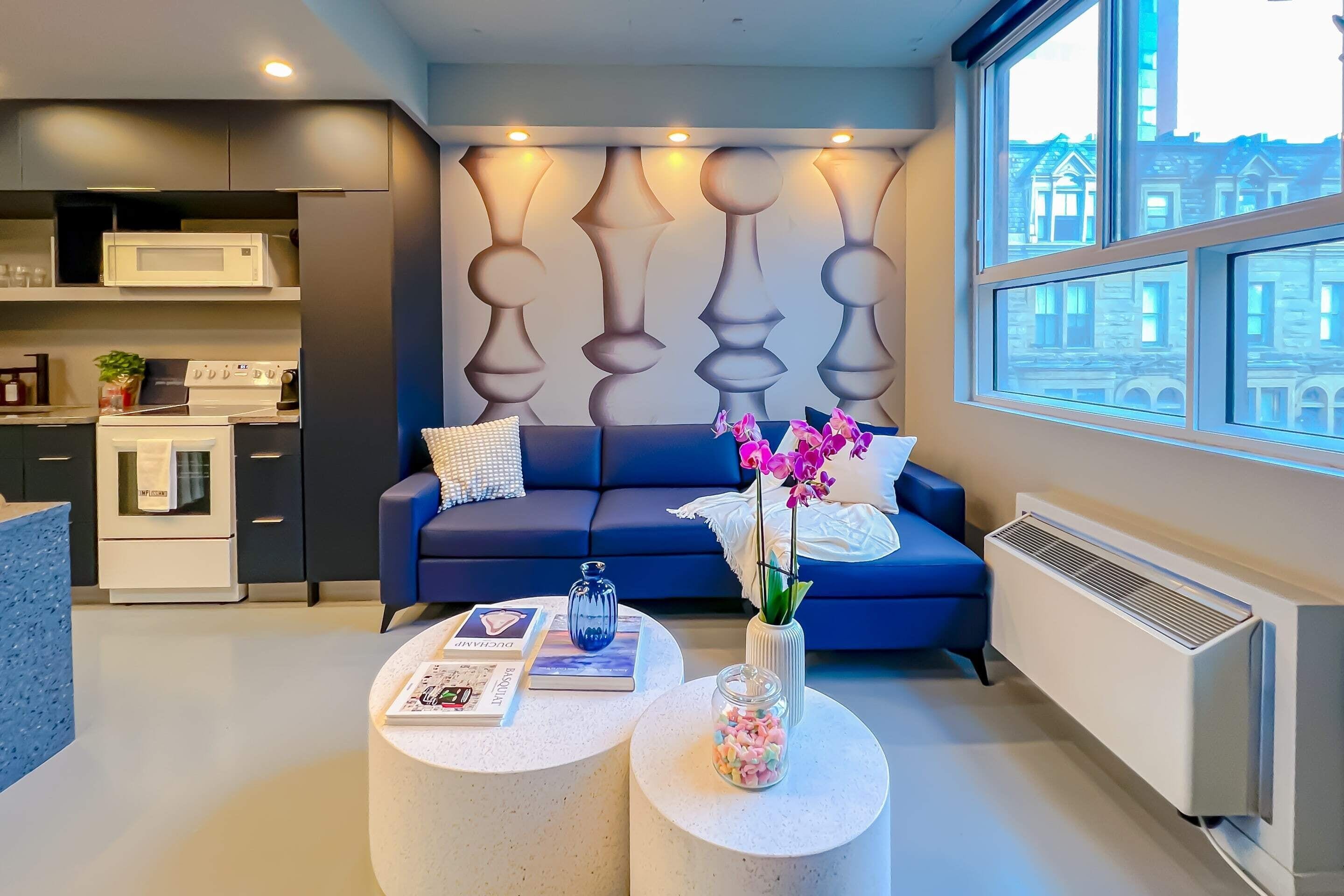 A modern living room with a blue sofa, a round coffee table, and a decorative wall panel.