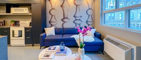 A modern living room with a blue sofa, a round coffee table, and a decorative wall panel.