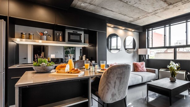 Una cocina moderna con una isla central, electrodomésticos integrados y un área de comedor con sofá y mesa de centro.