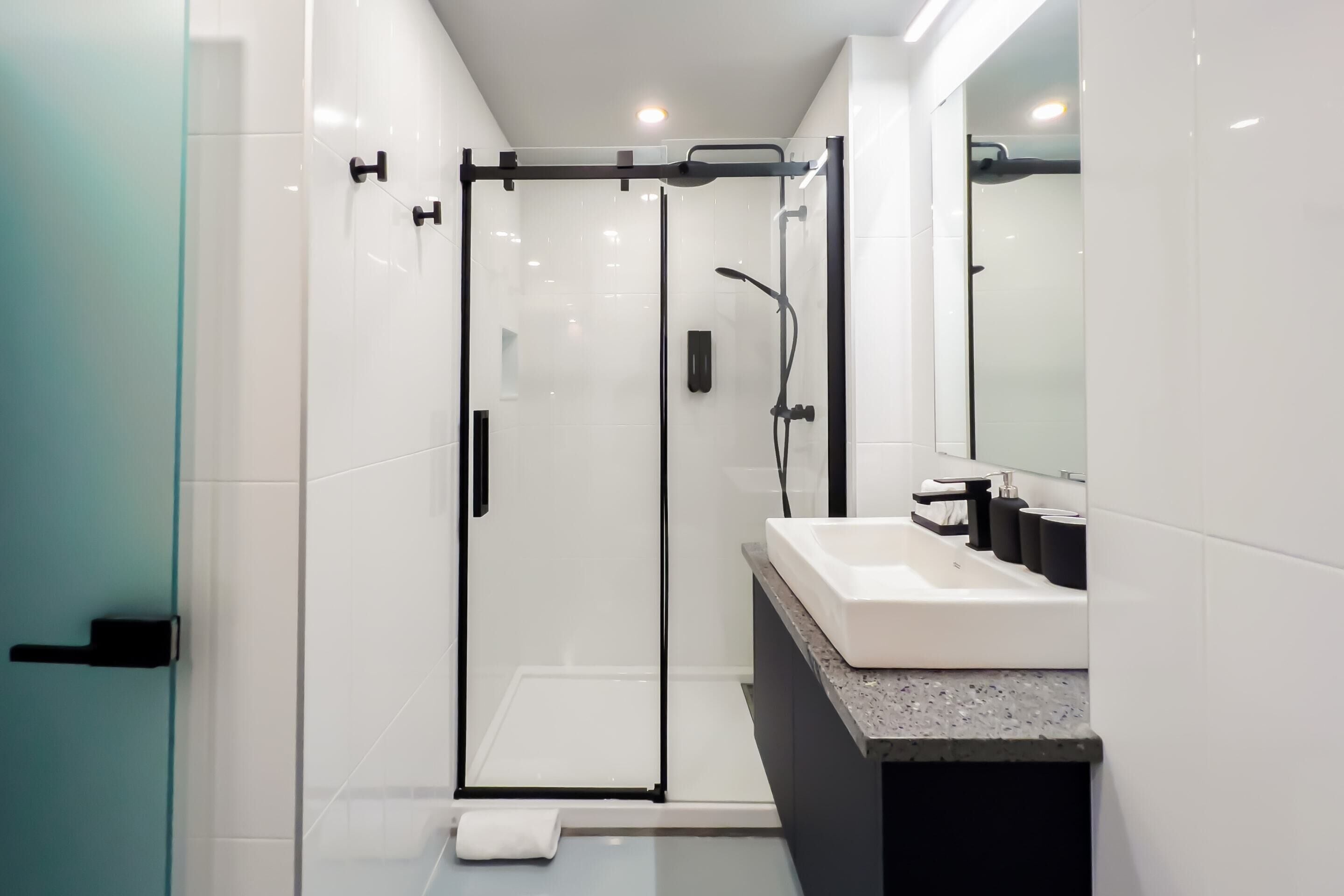 A modern bathroom with a glass-enclosed shower, a white sink, and a large mirror.
