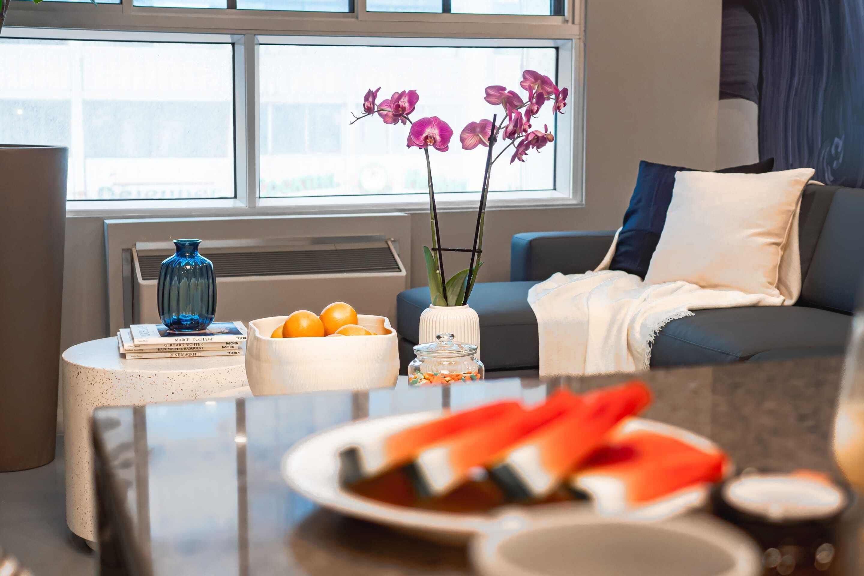 Un salon moderne avec un canapé, une table basse et une fenêtre laissant entrer la lumière naturelle.