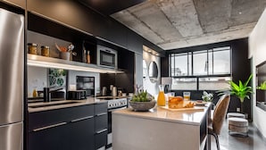 Una cocina moderna con una isla grande, electrodomésticos de acero inoxidable y vistas a la ciudad a través de amplios ventanales.