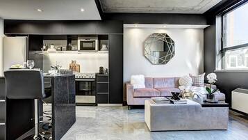 A modern kitchen with a built-in microwave, a dining area with a bar stool, and a living room with a sofa and a decorative wall piece.