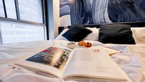 Una cama bien hecha con un libro, una taza y un pastel.