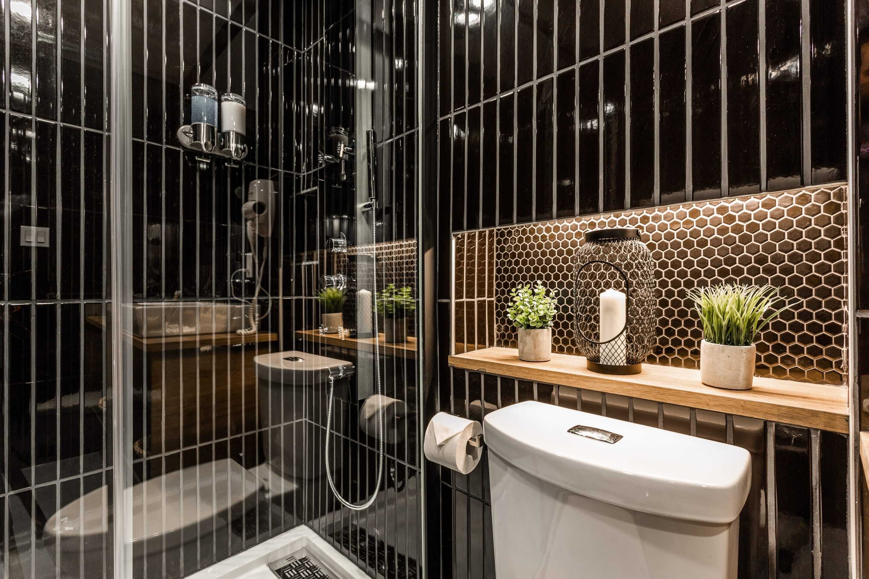 A modern bathroom with a glass shower enclosure, a toilet, and a vanity with a honeycomb tile backsplash.