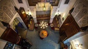 Um interior ornamentado com trabalhos em azulejos detalhados, um lustre central e um chão com padrão.